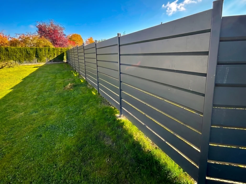 Portail coulissant aluminium anthracite (RAL 7016) à lames horizontales pleines avec section ajourée centrale en Z, monté entre deux piliers béton enduit