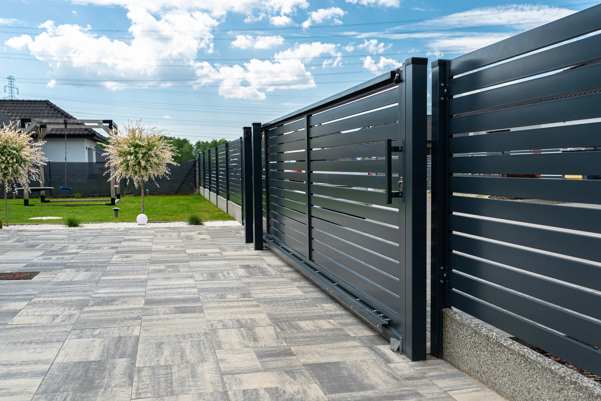Scène extérieure résidentielle avec portail coulissant moderne en aluminium anthracite à lames horizontales ajourées